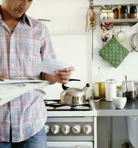 Man in his kitchen reading a newspaper