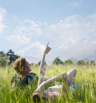 image showing two people lying in a field - one is pointing to the sky
