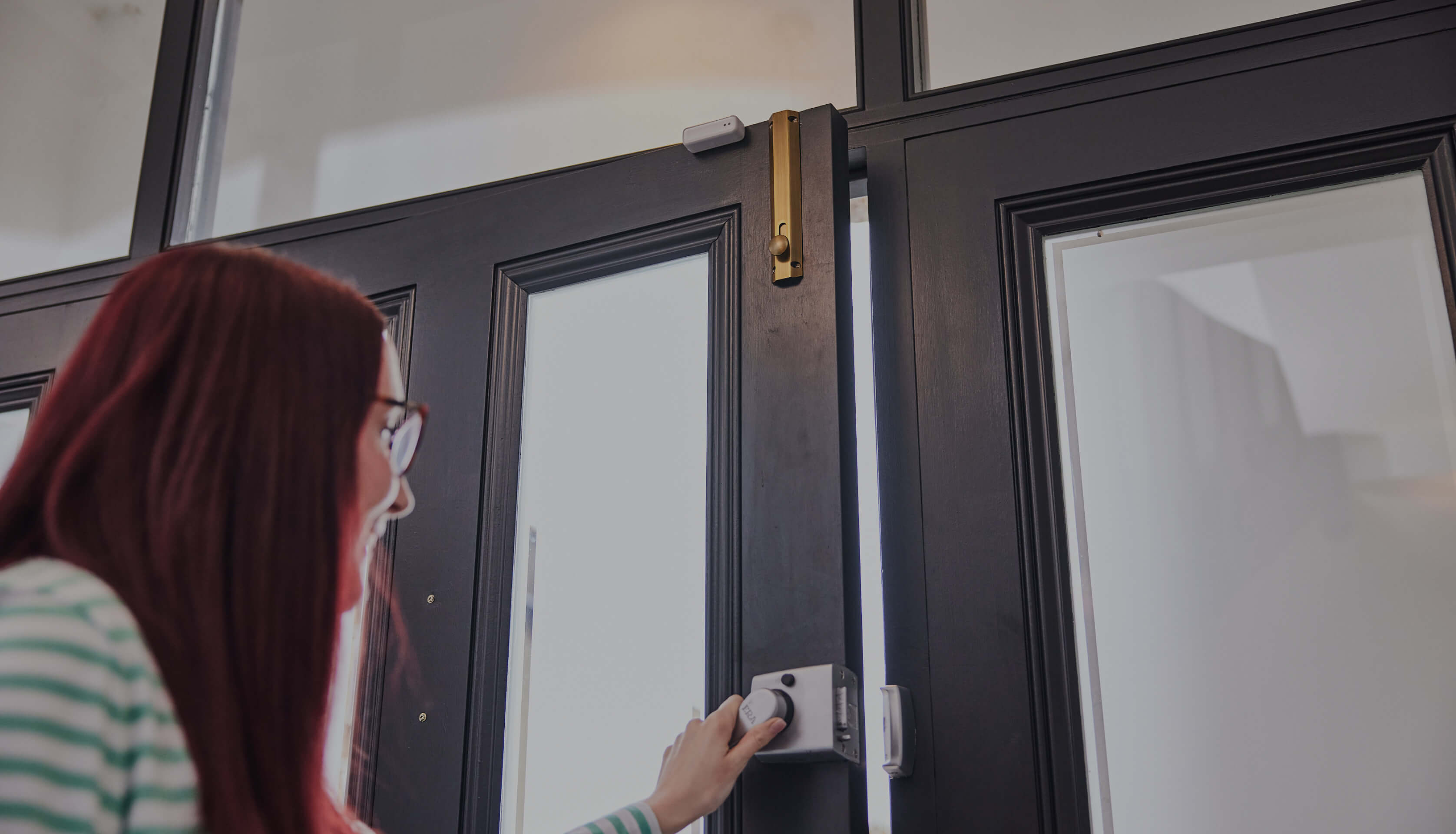 A Hive Home user opening their front door with a Hive Smart Door Sensor fixed to it.